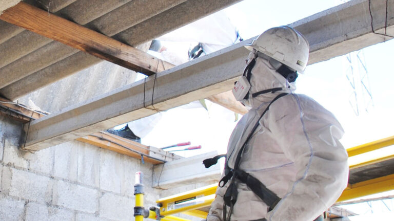 Licensed asbestos removal professionals safely dismantling an asbestos roof on a commercial building in Dorset.